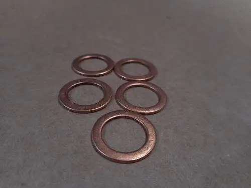 Runde Kupferdichtungen liegen auf einer flachen Oberfläche. Sie sind Teil von Remeha-Produkten zur Gewährleistung einer dichten Verbindung in Heizsystemen.